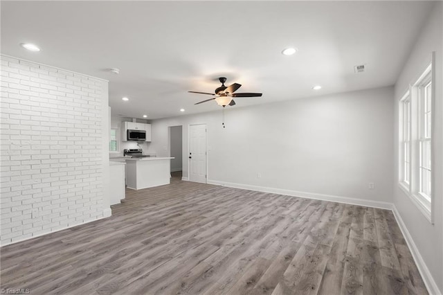 202 Aldridge Ln, Archdale, NC 27263 - unfurnished living room with light wood finished floors, ceiling fan, recessed lighting, baseboards, and brick wall