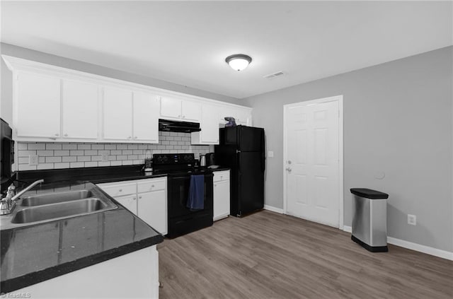 3304 Spring St, Greensboro, NC 27405 - kitchen with a sink, dark countertops, white cabinetry, black appliances, and under cabinet range hood