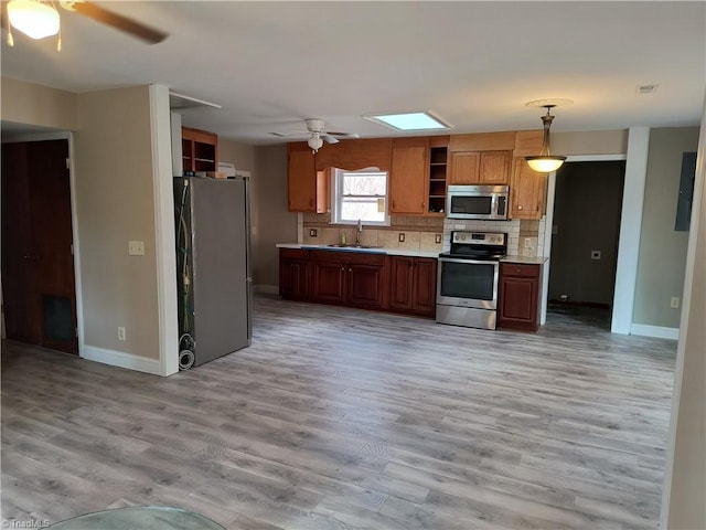 kitchen with light wood-style flooring, a sink, light countertops, appliances with stainless steel finishes, and open shelves