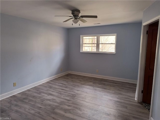 unfurnished room with visible vents, dark wood finished floors, baseboards, and ceiling fan