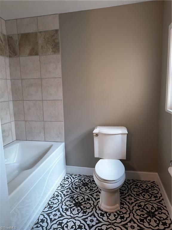 full bathroom featuring tile patterned flooring, toilet, and baseboards