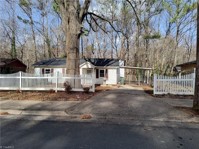 ranch-style house featuring a fenced front yard, driveway, and a carport