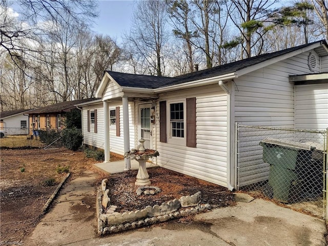 view of side of property featuring roof with shingles, fence, and central air condition unit