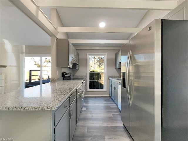 kitchen with light wood-type flooring, stainless steel appliances, beamed ceiling, and gray cabinetry