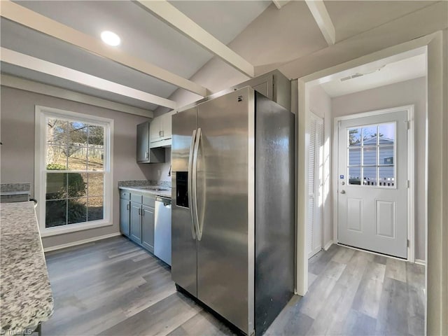 kitchen with light wood-type flooring, appliances with stainless steel finishes, gray cabinetry, and beam ceiling