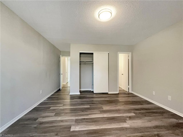 unfurnished bedroom with a textured ceiling, a closet, and dark hardwood / wood-style flooring