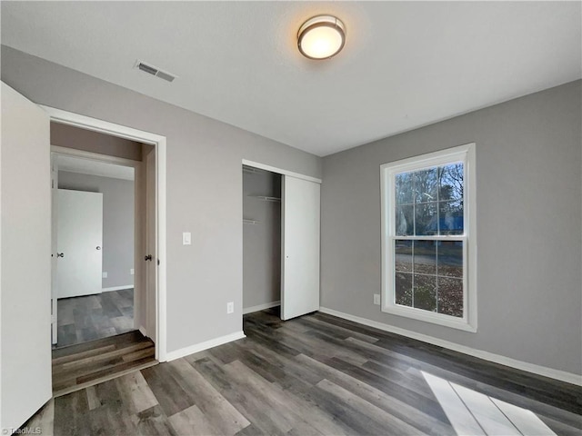 unfurnished bedroom featuring dark wood-type flooring and a closet