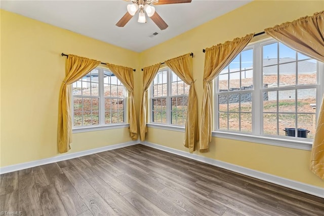 empty room featuring a ceiling fan, baseboards, and wood finished floors