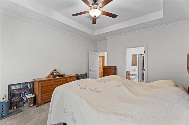 bedroom featuring a raised ceiling, ensuite bathroom, ornamental molding, a ceiling fan, and light carpet