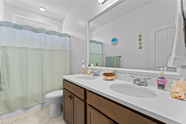 bathroom featuring marble finish floor, double vanity, a sink, and toilet