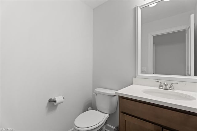 bathroom featuring baseboards, vanity, and toilet