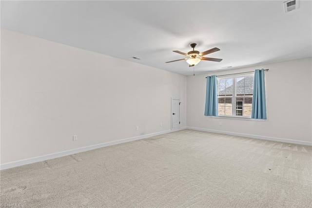 spare room with light colored carpet, visible vents, ceiling fan, and baseboards