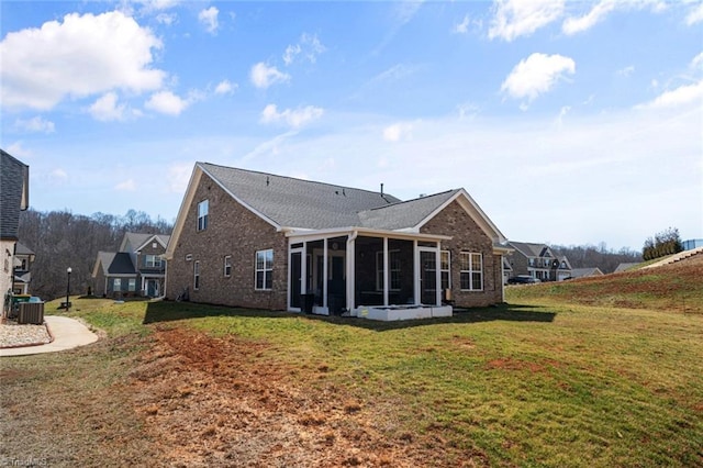 rear view of house with brick siding, a lawn, a sunroom, and central air condition unit