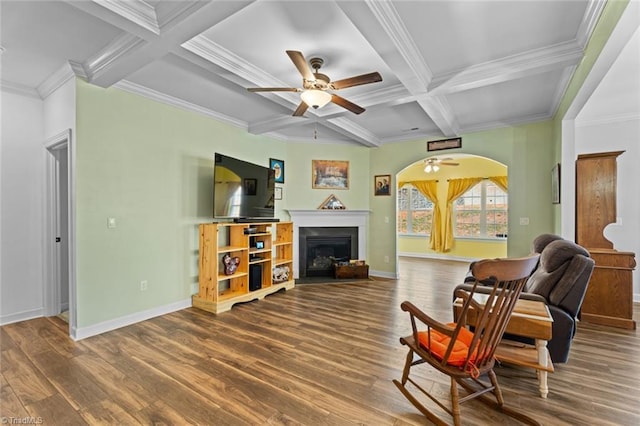 sitting room with arched walkways, a fireplace, wood finished floors, beamed ceiling, and baseboards