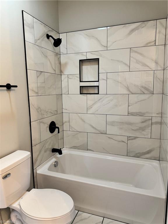 bathroom featuring tiled shower / bath combo and toilet