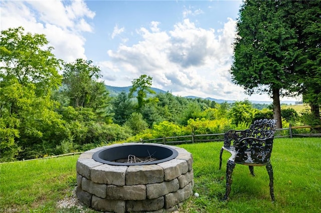 view of property's community with a mountain view, a lawn, and an outdoor fire pit