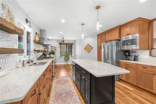 kitchen featuring open shelves, light wood-style flooring, a sink, appliances with stainless steel finishes, and wall chimney range hood