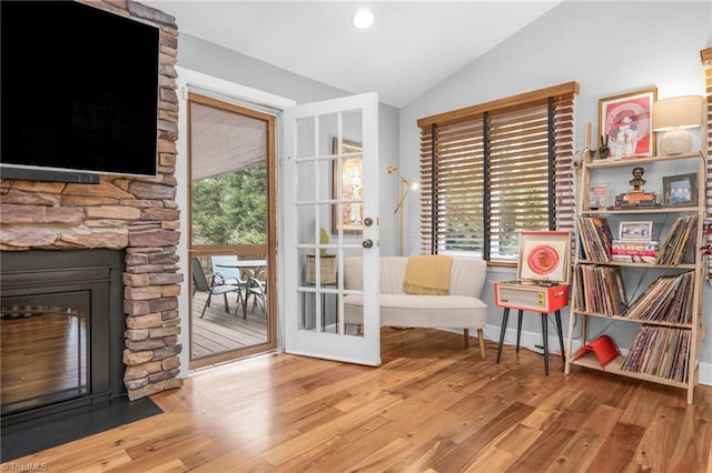 doorway featuring a fireplace, baseboards, lofted ceiling, and wood finished floors