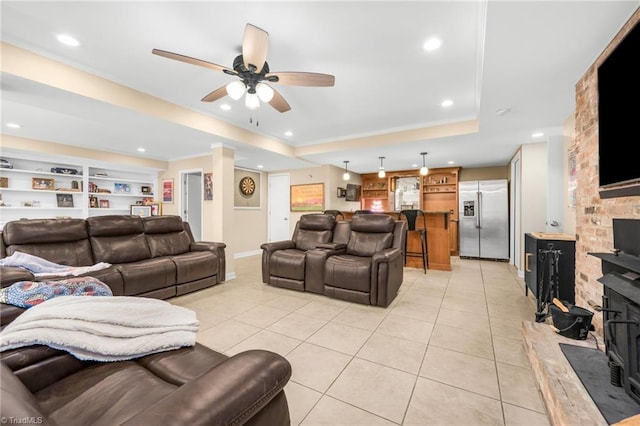 living room featuring ceiling fan, a tray ceiling, light tile patterned floors, and built in features