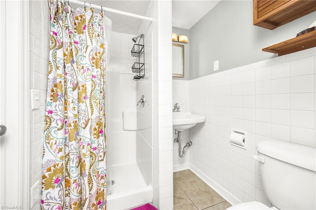 full bathroom featuring a stall shower, wainscoting, tile walls, toilet, and tile patterned floors