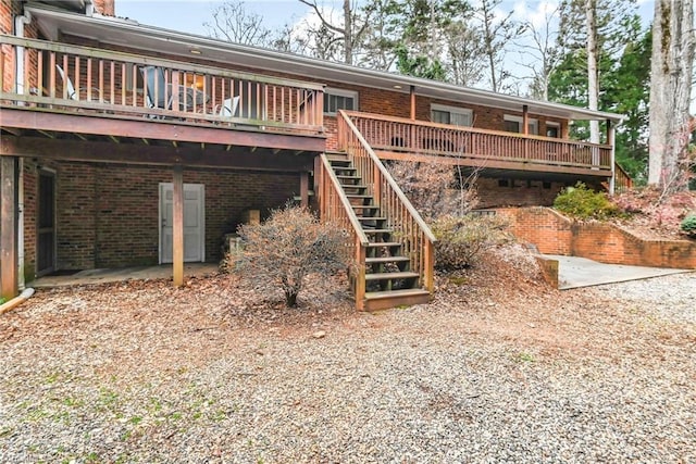 rear view of property with stairs, brick siding, and a wooden deck