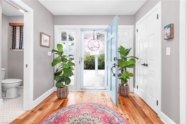 entryway featuring a notable chandelier, light wood-type flooring, and baseboards