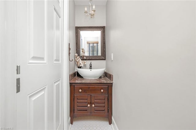 bathroom with baseboards, an inviting chandelier, and vanity