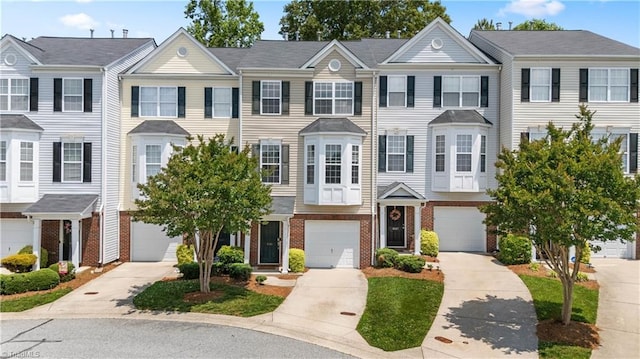 townhome / multi-family property with driveway, brick siding, and an attached garage