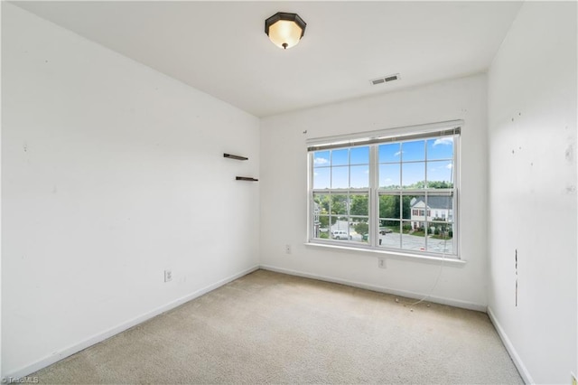 spare room featuring light colored carpet and baseboards