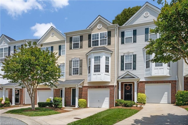 townhome / multi-family property featuring an attached garage, driveway, and brick siding
