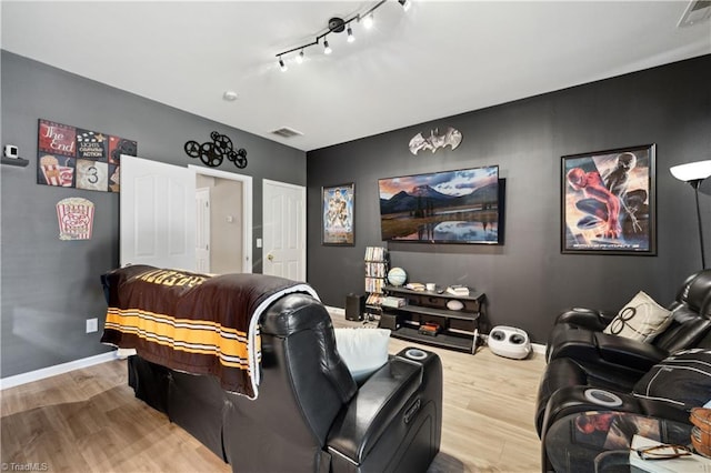 home theater room featuring wood finished floors, baseboards, and track lighting
