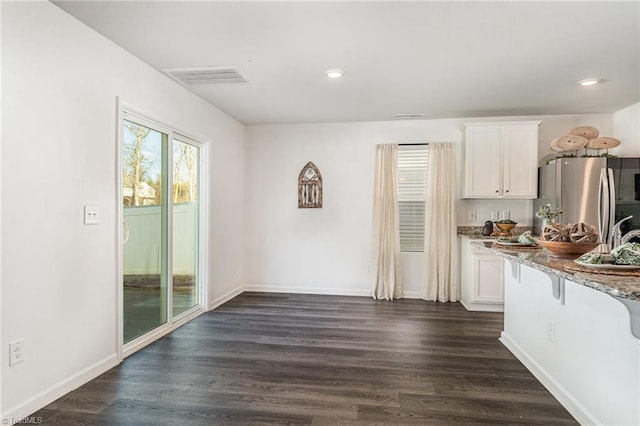 kitchen with white cabinetry, light stone countertops, dark wood-type flooring, and stainless steel fridge