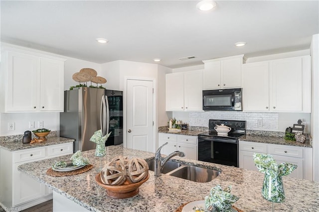 kitchen with sink, white cabinetry, light stone counters, black appliances, and decorative backsplash