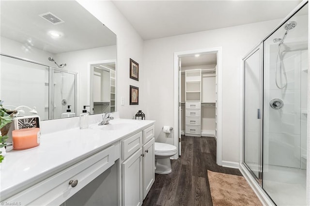 bathroom featuring a shower with door, vanity, wood-type flooring, and toilet