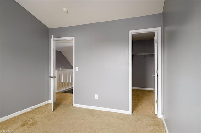 unfurnished bedroom featuring light carpet and a walk in closet