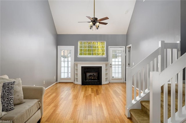 living room featuring hardwood / wood-style flooring, ceiling fan, and high vaulted ceiling