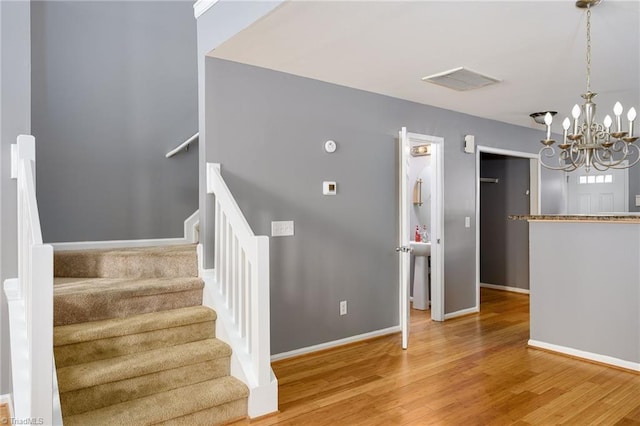 stairway featuring wood-type flooring and a chandelier