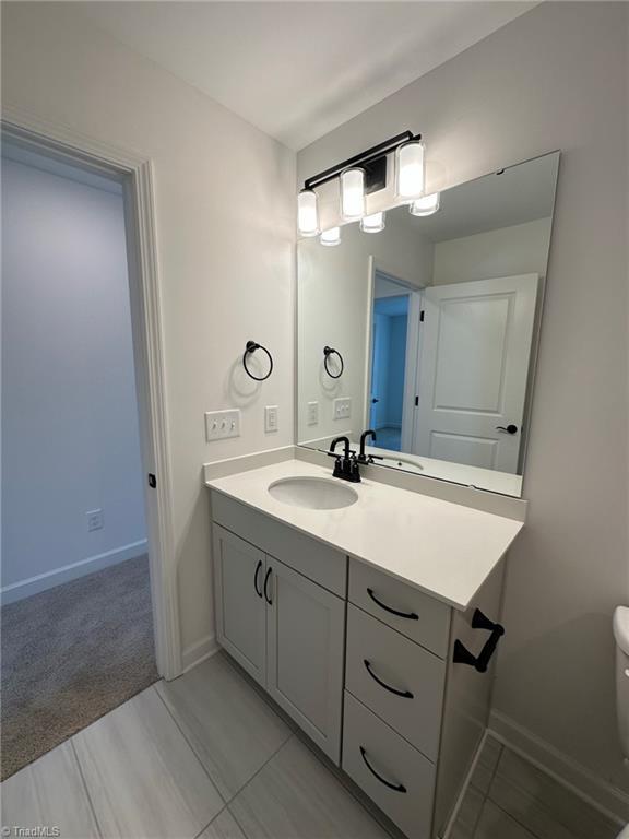 bathroom featuring tile patterned flooring, vanity, and toilet