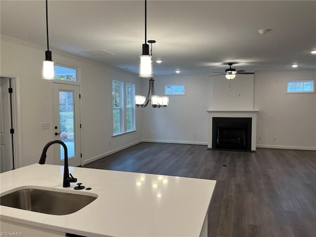 kitchen with dark hardwood / wood-style flooring, crown molding, sink, and hanging light fixtures