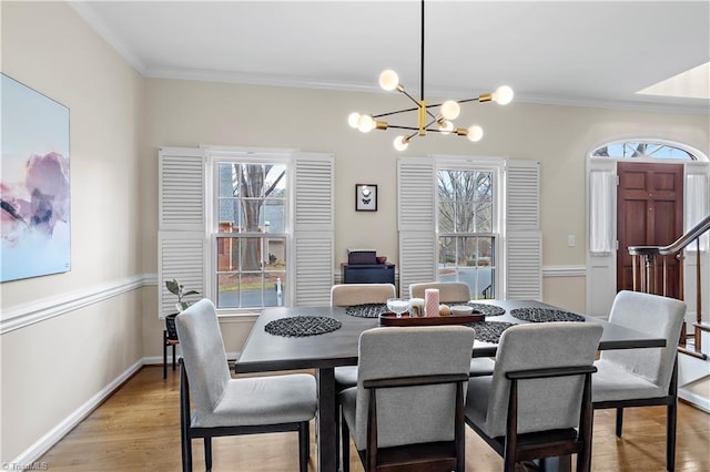 dining area featuring light wood-style floors, a notable chandelier, ornamental molding, and baseboards