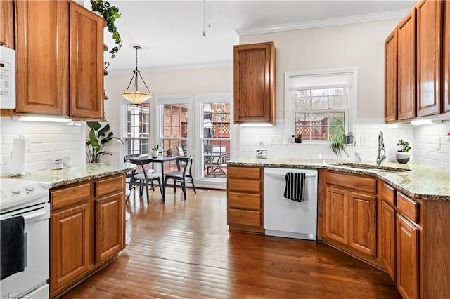 kitchen with white appliances, pendant lighting, a sink, and brown cabinetry