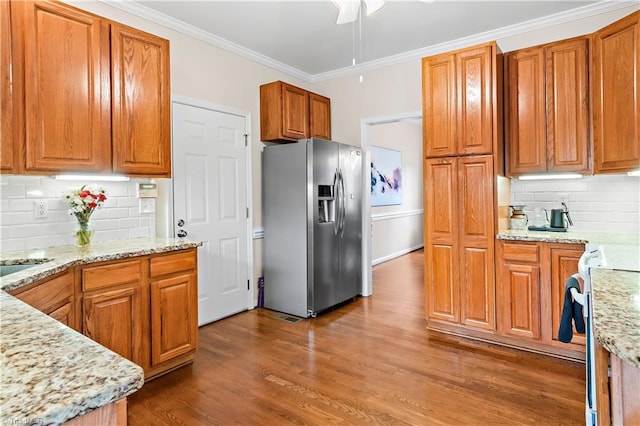 kitchen featuring range, stainless steel fridge with ice dispenser, light stone counters, dark wood-style flooring, and crown molding