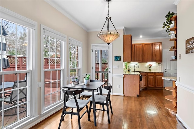 dining area with dark wood-style floors, crown molding, and baseboards