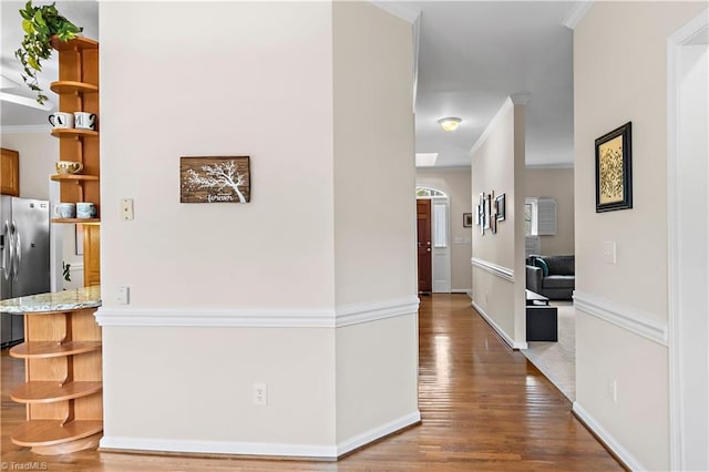 corridor with crown molding, baseboards, and wood finished floors