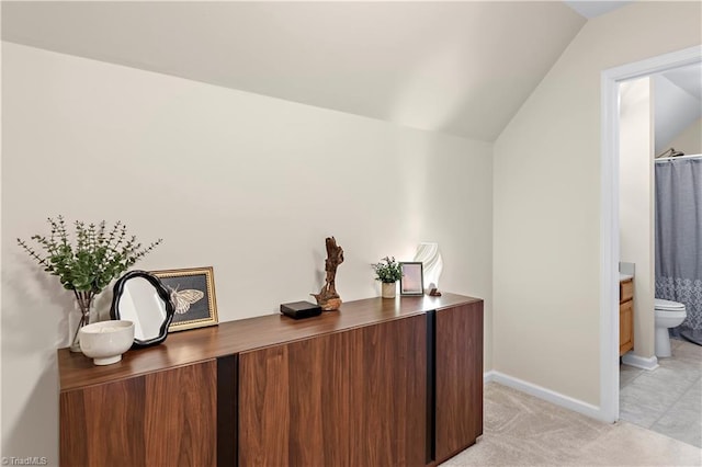 interior space featuring lofted ceiling, light carpet, and baseboards