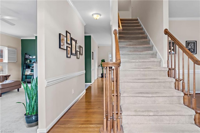 stairs featuring ceiling fan, baseboards, crown molding, and wood finished floors