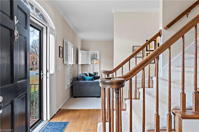 foyer featuring ornamental molding, light wood-style flooring, baseboards, and stairs