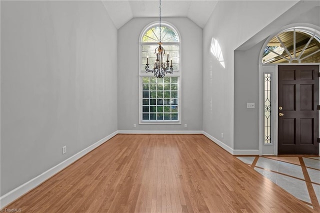 entryway featuring hardwood / wood-style floors, a chandelier, and vaulted ceiling