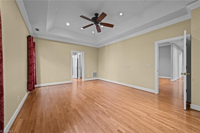 unfurnished room with ornamental molding, light wood-type flooring, ceiling fan, and a raised ceiling