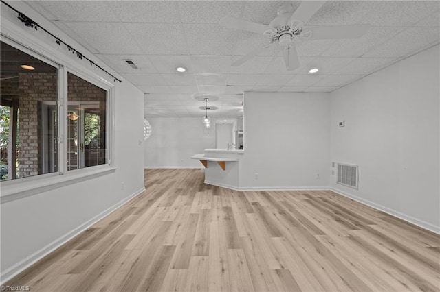 unfurnished living room featuring a paneled ceiling, light hardwood / wood-style floors, and ceiling fan